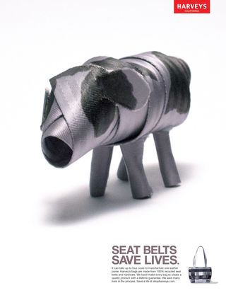 A gray seatbelt with black spots fashioned to look like a cow, with the copy 'Seat belts save lives' in the bottom right corner